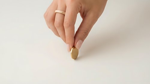 Woman hand holding golden coin on white background for financial investment and savings concept.