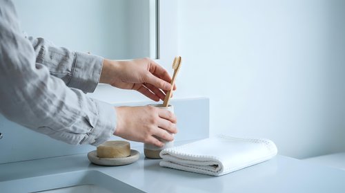 Professional woman writing handwritten note at clean white desk with coffee cup and notebook in bright modern office workspace for business communication.