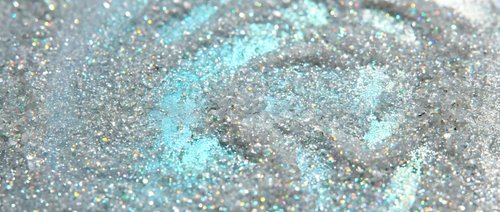 Shimmering holographic glitter texture with turquoise and silver sparkles creating magical rainbow reflections for luxury cosmetic and fashion backgrounds.