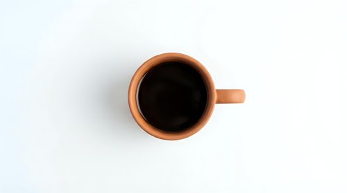 Orange ceramic coffee mug with black coffee viewed from above on white background, isolated for design use in branding and promotional materials.