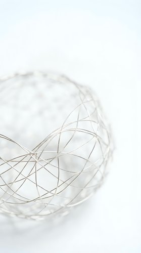 Modern wire mesh sphere on white background showcasing geometric patterns and metallic finish for contemporary design projects.