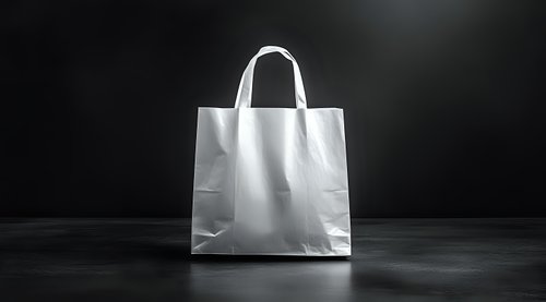 White paper shopping bag with handles on dark background for retail branding and packaging design mockup projects.