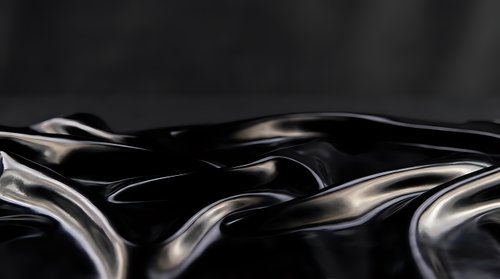 Abstract liquid metal waves with glossy reflective surface creating dynamic flowing patterns on dark background for modern design projects.